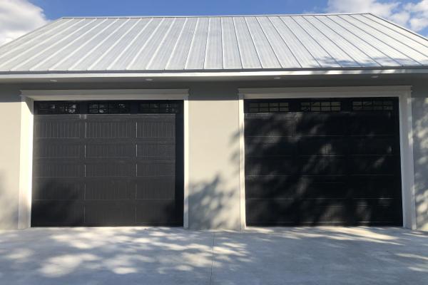 New construction project with oversized doors. Homeowner was looking for a unique look for the garage and chose raised long panel carriage stamp garage doors in black with long panel glass and stockton inserts.