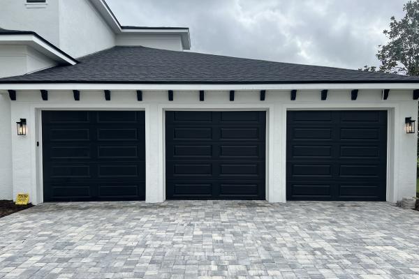 Recently constructed home with three raised long panel garage doors in custom color. 