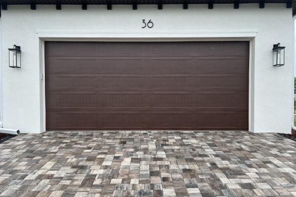 New construction home with stamped carriage long panel garage door in custom color.